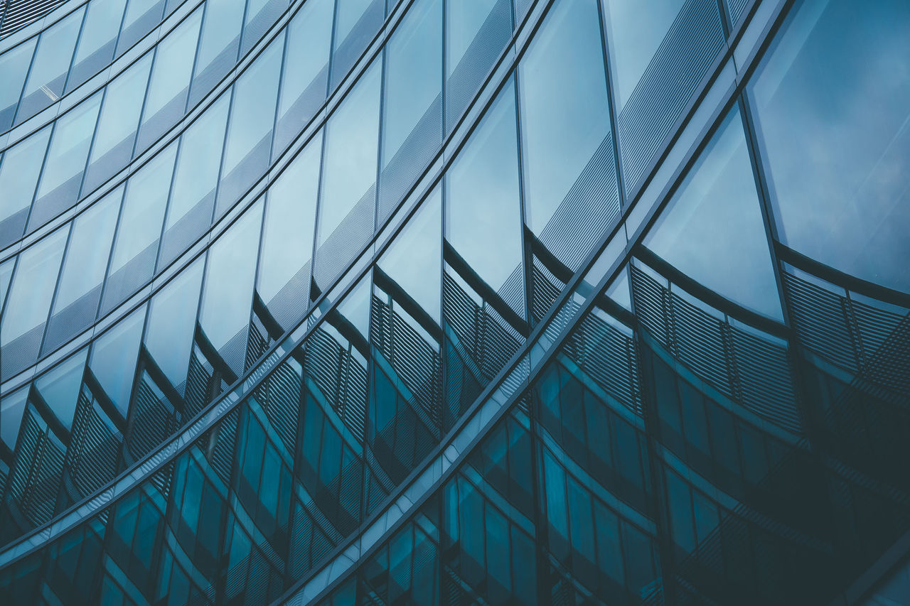 Abstract business modern city urban futuristic architecture background. Real estate concept, motion blur, reflection in glass of high rise skyscraper facade, toned blue picture with bokeh